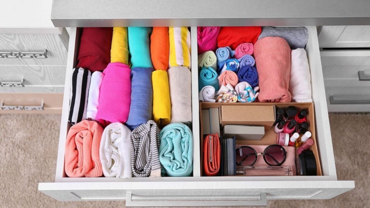 Mujer doblando camisetas con técnica KonMari en cajón organizador"